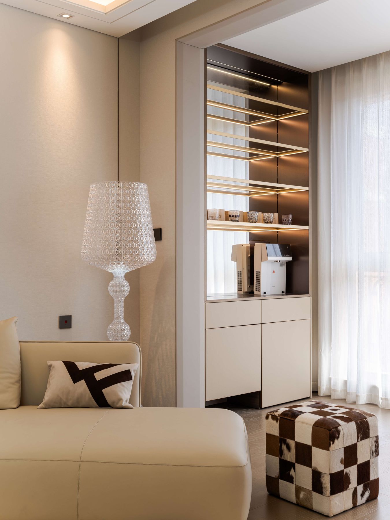 Bar unit with lit glass shelves above cream cabinets