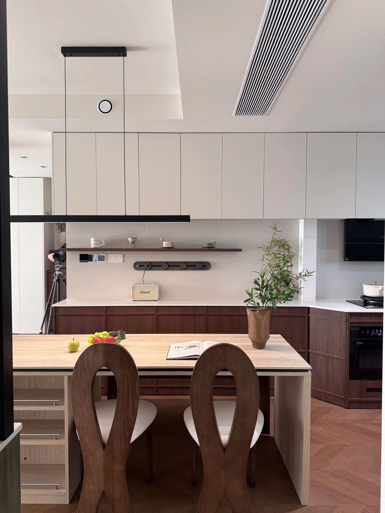 Open kitchen with walnut fluted base cabinets, white wall cabinets and a sintered-stone island