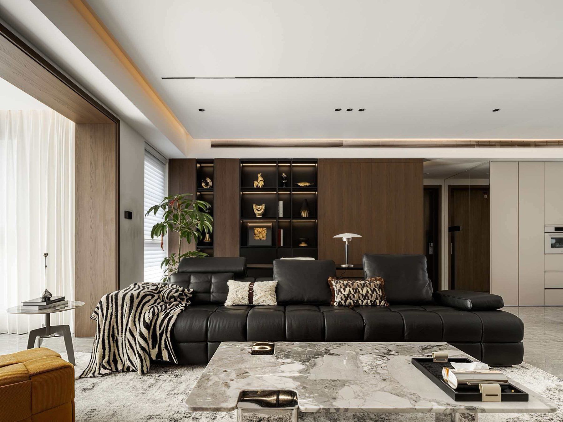 Living room with a black-framed lit display cabinet, timber wall panelling and a concealed door