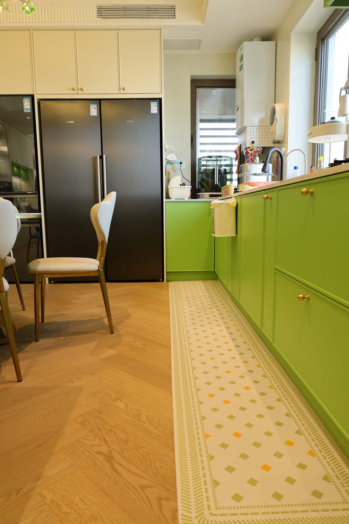 Galley kitchen with green base cabinets and a tall fridge unit