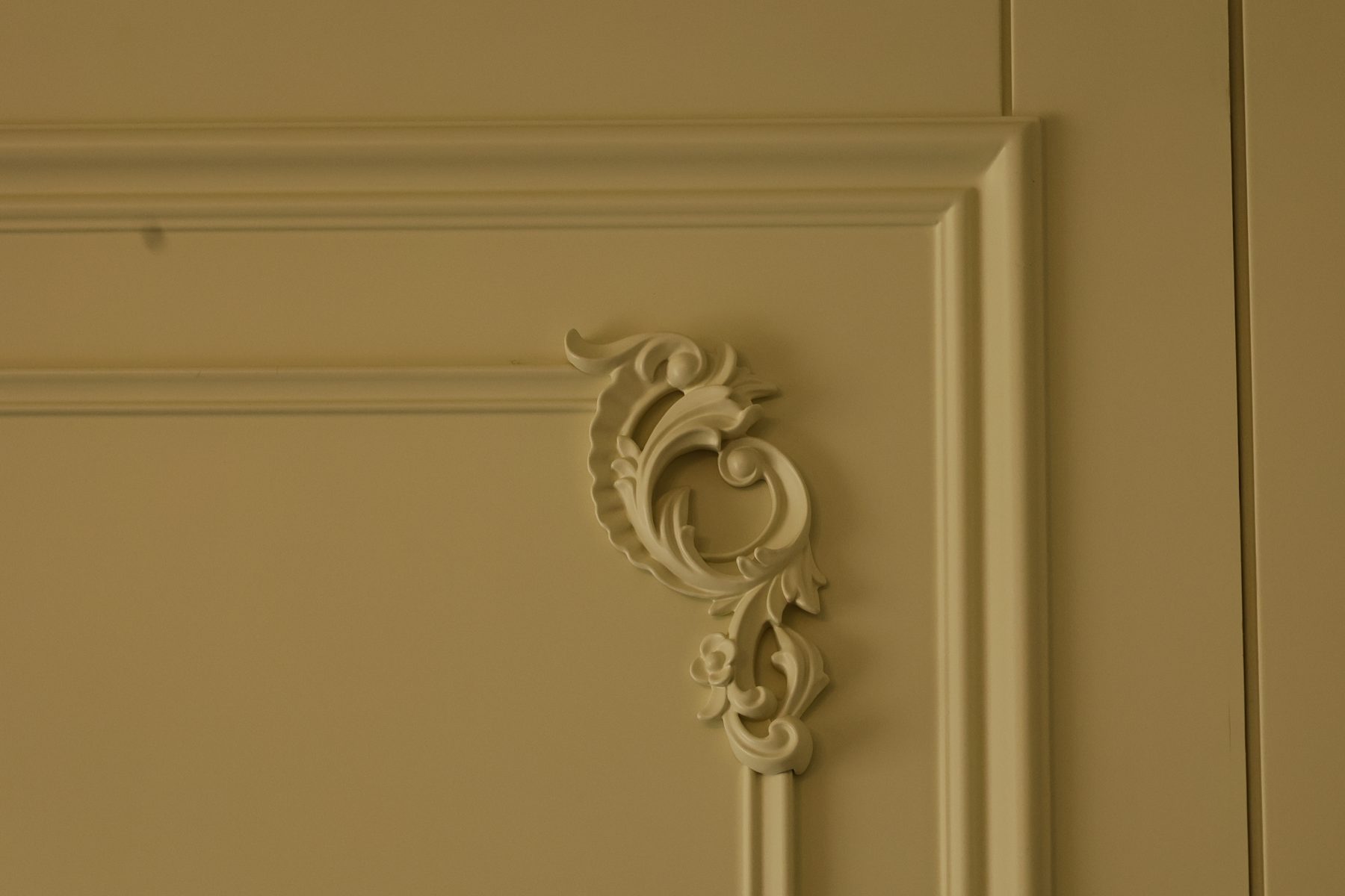 Close-up of carved corner mouldings on cream wall panelling